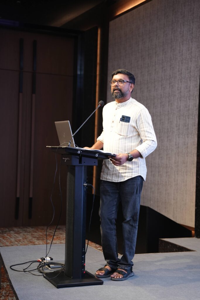 A photo of Prof. Arul George Scaria speaking at an event.
